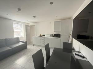 a white living room with a couch and a kitchen at Coastal Plaza in Blackpool