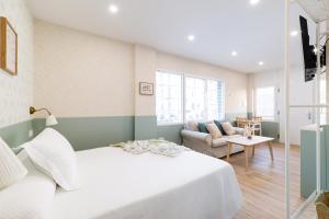 een slaapkamer met een wit bed en een bank bij Estudio reformado en Granada in Granada