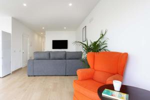a living room with an orange chair and a couch at Las Ranas 1 in El Durazno