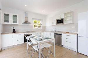 a kitchen with white cabinets and a table with chairs at Las Ranas 1 in El Durazno