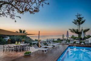 een terras met een tafel en stoelen naast een zwembad bij VILLA PROVENZA 12&4, Emma Villas in Cefalù