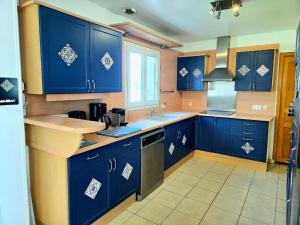 a kitchen with blue cabinets and a sink at Maison Familiale & Confortable proche Plage in Luc-sur-Mer
