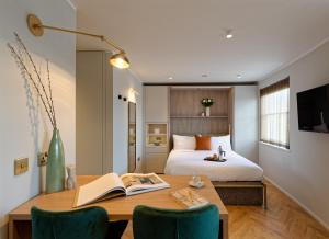 Dormitorio con cama y escritorio con libro en South Kensington Studios by D'Montrio, en Londres