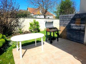a white table and a barbecue grill on a patio at Maison Familiale & Confortable proche Plage in Luc-sur-Mer