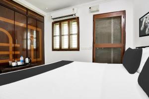 a bedroom with a white bed and a wooden door at Super Hotel O J3 LUXURY ROOMS in Guntūr +25 photos
