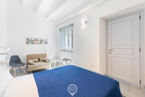 Un dormitorio blanco con una cama azul y una silla en Rosa dei Venti Guesthouse, en Cabras