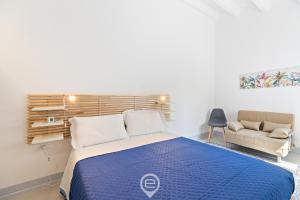 Un dormitorio con una cama azul y un sofá. en Rosa dei Venti Guesthouse, en Cabras