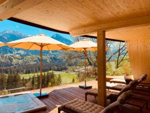 a wooden deck with a pool and umbrellas at Hotel Bergflair in Fischen