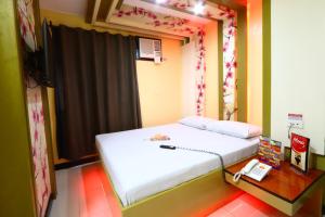 a bedroom with a bed and a telephone and a table at Hotel Sogo Makati Avenue in Manila +15 photos
