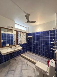 Un baño con azulejos azules, inodoro y lavabo. en Woodside Retreat Pangot By Royal Collection Hotels, en Nainital