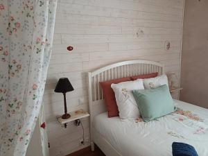a bedroom with a white bed with colorful pillows at O'TY'ZOISEAUX - Plus proche de la nature - Meublé tourisme classé 4 étoiles in Scaër
