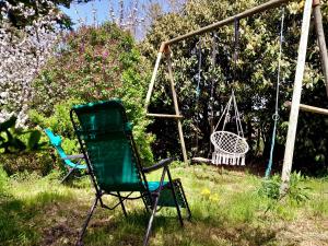 a green chair and a swing in a yard at Studio à la campagne, Jardin, Lac à 7 min in Chenereilles
