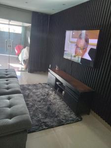 a living room with a couch and a flat screen tv at Casa de alto padrão in Macacos