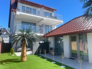 a house with a palm tree in front of it at Apartamenty AQUA MAZURY in Ełk