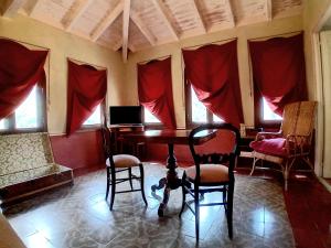 Pokój ze stołem, krzesłami i czerwonymi zasłonami w obiekcie La Casa Rosa w mieście Pigna