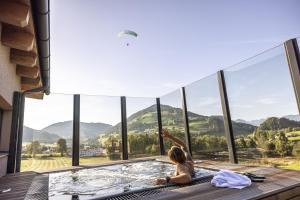 a child in a hot tub with a view of mountains at Alpine Collection Wildschönau in Niederau