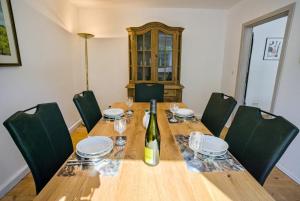 a wooden table with green chairs and a bottle of wine at FeWo Römerweg in Neustadt an der Weinstraße