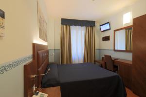 a room with a bed and a desk and a window at Hotel Terminus & Plaza in Pisa