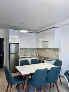 a kitchen with a white table and blue chairs at Mehmeti Apartment in Sarandë