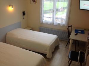 a room with two beds and a table and a desk at Le Relais de la route bleue in Saint-Loup