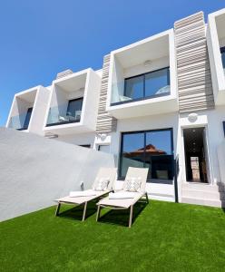 two chairs on a lawn in front of a house at MEDANO4YOU Arecas Del Mar in El Médano