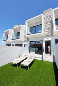 a white house with lawn chairs in front of it at MEDANO4YOU Arecas Del Mar in El Médano +35 photos