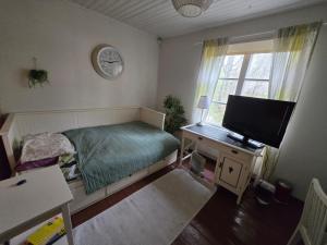 a bedroom with a bed and a desk with a television at Private room in a 250 years old house in Helsinki +2 photos