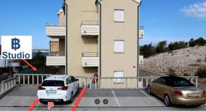 two cars parked in a parking lot in front of a building at Apartment IB Studio Pag6 in Kustići