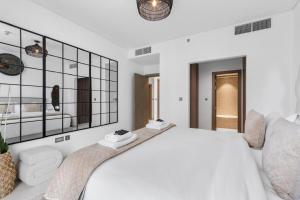 ein weißes Schlafzimmer mit einem großen Bett und einem Spiegel in der Unterkunft Luxurious 1 BR in District One Beach Access in Dubai + 16 Fotos