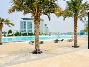 eine Gruppe von Palmen am Strand mit Pool in der Unterkunft Luxurious 1 BR in District One Beach Access in Dubai