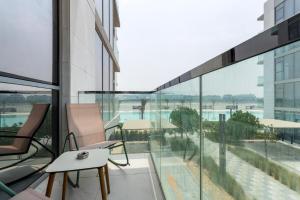 einen Balkon mit Glasfenstern sowie einem Tisch und Stühlen in der Unterkunft Luxurious 1 BR in District One Beach Access in Dubai
