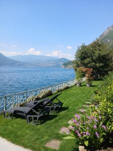 two picnic tables on the grass next to the water at La Casina a Remi in Marone