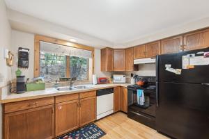 a kitchen with wooden cabinets and a black refrigerator at Sagamore 46G - Adirondack Retreat for All Seasons in North Creek