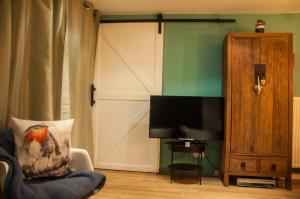 a living room with a tv and a couch and a chair at Chalet Klein Geluk in Lanaken