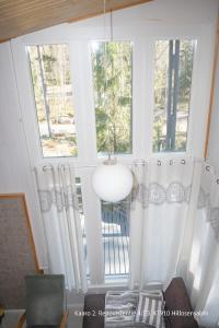 a room with two large windows with white curtains at Villa Repovesi in Hillosensalmi