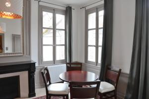 een eetkamer met een tafel, stoelen en ramen bij Maison du chatelain in Saint-Aignan