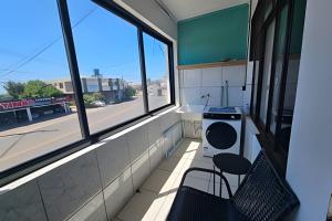 a room with a counter and two chairs and a window at AP104 - Amplo AP no centro c/ AC in São Miguel dʼOeste