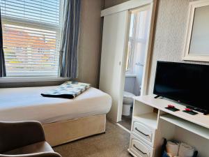 a small hotel room with a bed and a television at Cwtch Guesthouse in Llandudno