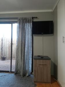 a living room with a tv and a curtain at Tevrede Guest Cottage in Bloemfontein +8 photos
