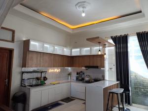 a kitchen with white cabinets and a counter top at Teras Senja Sikunir in Kejajar