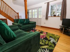 a living room with a green couch and a television at The Baler House in Hayle