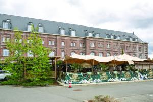 ein Gebäude mit einem Restaurant mit Sonnenschirmen davor in der Unterkunft Hotel Verviers Van der Valk in Verviers