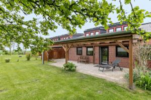 a brick house with a patio and grass at Ferienhof Littmann in Friedrich-Wilhelm-Lübke-Koog