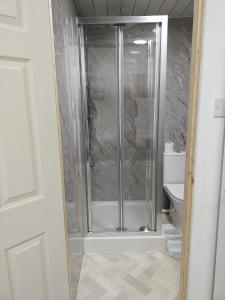 una ducha con puerta de cristal en un baño en Bet El Cozy & Comfy Room 4, en Parkside