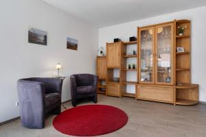 un soggiorno con 2 sedie e un tappeto rosso di Ferienwohnung Rebenrain, 80qm a Steinach