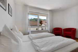 una camera da letto bianca con due letti e una finestra di Ferienwohnung Rebenrain, 80qm a Steinach