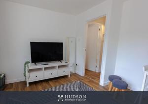 a living room with a flat screen tv on a white cabinet at 1-Bedroom Apartment with Parking in Wellington
