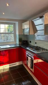 a kitchen with red cabinets and a stove top oven at Roserin Coorie, Perth - just a few minutes walk from the city centre! in Perth