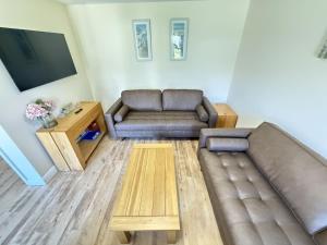 a living room with a couch and a tv at Jolly Roger Cottage - Part of the The Bay Filey Holiday Village with pool, gym and direct beach access, pub, restaurant, tennis and meadows walks in Filey