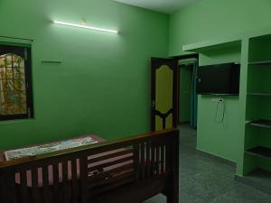 a green room with a bed and a television at La Rasamb sejour villa in Kottakupam